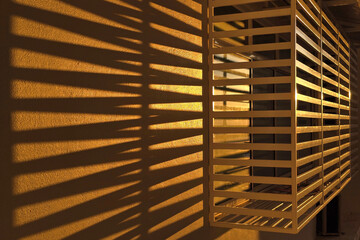 Golden Sunlight Casting Shadow Lines Through Window Grille on Wall