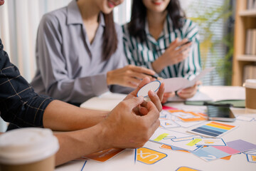 Designers having a UX/UI planning meeting to refine mobile app layouts and user flow. They collaborate closely to create functional and visually appealing interface solutions.