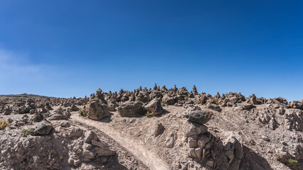 High mountain landscape. A land devoid of vegetation. Piles of boulders on the ground and pyramids made of stones. The blue sky. Copy space. Peru. Abra Patapampa 