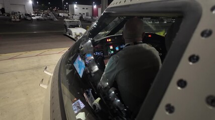 An external view through the cockpit window, of a pilot doing the pre-flight checks before the first flight of the day at night, with a side view of the cockpit of a modern jet. - Powered by Adobe