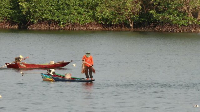 Fisherman Casting Net from Long-tail Boat in Tropical River in chanthaburi Thailand.