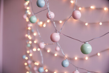 Pastel sphere garland on pink wall with warm bokeh glow, soft lights create dreamy ambiance and festive mood, delicate decoration evokes cozy charm for holiday party and nursery decor