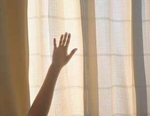 Hand touching sheer curtain in soft morning light, peaceful intimate moment with gentle texture