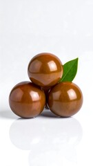 Three Kumato Tomatoes with Leaf on White Reflective Surface.