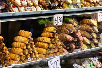 A tempting window display of stacked Sicilian Cannoli pastries in Venice, featuring classic, pistachio, and amaretto flavors, with handwritten price tags showcasing Italian street food.

