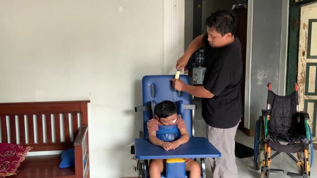 A father carefully feeds a child with cerebral palsy, using a syringe in a home setting, highlighting dedicated care and support.