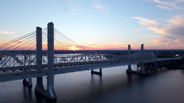 Aerial over Abraham Lincoln Bridge in Kentucky during sunset with vibrant colors in the sky while cars pass over to get to Indiana 