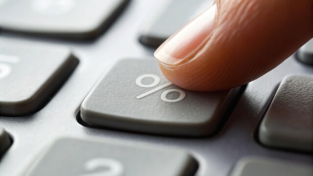 A close-up of a finger pressing the percentage key on a gray calculator, illustrating financial calculations or data analysis.