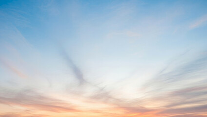 Sky with clouds showing blue and orange colors at sunrise or sunset, glowing warmly across the horizon and reflecting a peaceful natural beauty that inspires calm.