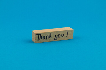 Small wooden block with handwritten thank you message on blue background