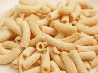 Crunchy macaroni snacks, piled on white background
