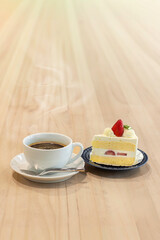 Delightful cup of coffee paired with a slice of strawberry cake on a wooden table in a cozy cafe setting