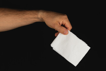 Hand holding a white napkin in a dark setting
