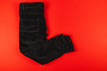 Black jeans on a red background in a simple flat lay display