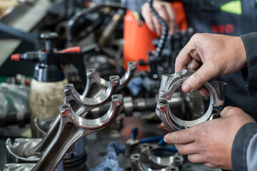 Obraz premium Automotive technician inspecting connecting rod at car workshop, detailed view of engine components, auto repair process, mechanical precision and industrial maintenance scene.