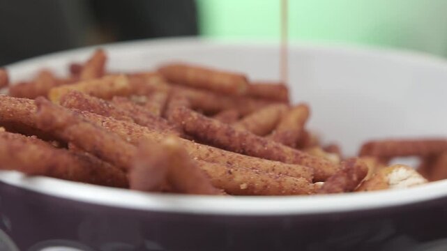Close-up of pretzels in a bowl with chocolate being poured over