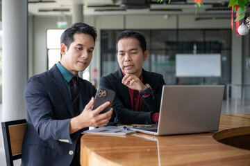 Businessmen using smartphone and laptop are discussing about work