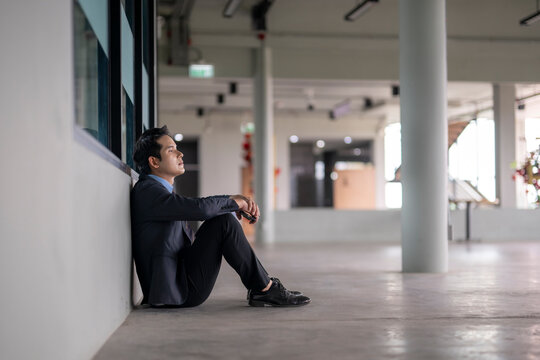 Stressed businessman sitting on floor in empty office contemplating next move