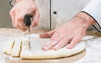 Chef s hands skillfully cutting dough on a floured surface