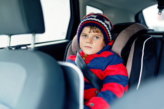 Little kid boy sitting in safety car seat during trip