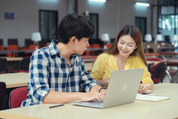 Group of students studying together in library. Two Asian students learning and discussing in a library at the university.