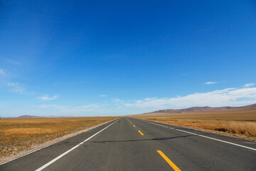 Naklejka premium Endless straight road stretching under clear blue sky