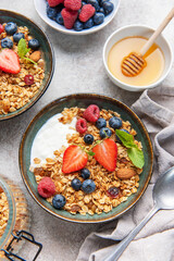 Granola bowls with berries, yogurt, nuts, and honey for breakfast