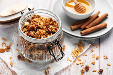 Homemade honey granola in jar with cinnamon sticks