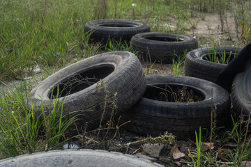 Illegal dumping of used rubber tires in a field, an environmental problem.