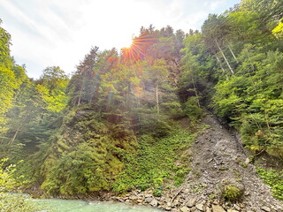 Panorama of the sun's rays illuminating the coastal slope of the mountain river, creating an incredible picture of a natural veil of rainbow colors.