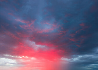 Dramatic sky with storm clouds illuminated by red sunset or sunrise. Vivid colorful cloudscape for nature banner or weather background. Bright sunset or sunrise light.