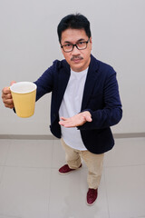 Closeup shot of man offering hot drink in yellow ceramic cup