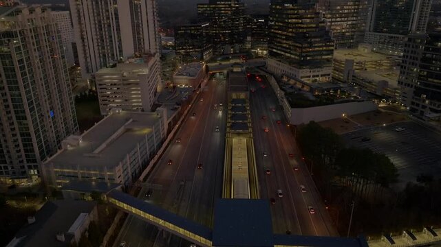 T Harvey Mathis Parkway, State Route 400 through Buckhead affluent district with modern commercial skyline buildings in view at night, Atlanta, Georgia, Aerial