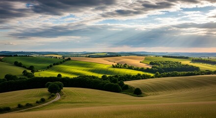 Obraz premium Rolling hills and sunbeams create a picturesque landscape on a cloudy day