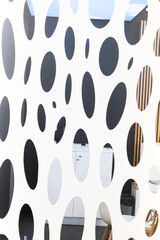 Abstract wall with an intricate pattern of black and white ovals and circles. The dynamic composition and clean design t for a travel reel highlighting contemporary urban spaces or design.