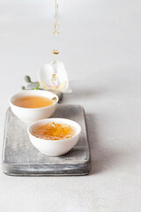 Close-up of golden tea stream filling ceramic cups, soft light and clean background enhance the serene, zen-inspired aesthetic, perfect for wellness or lifestyle themes.