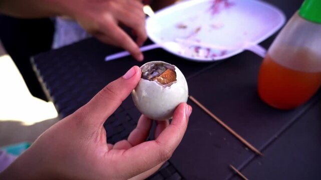 Asian girl eating traditional dish balut fertilized duck or chicken embryo in egg cooked boiled