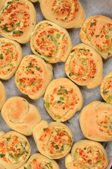 An overhead view shows numerous freshly baked dough rolls filled with melted Parmesan, garlic, and...