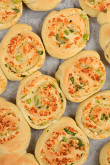 An overhead view shows numerous freshly baked dough rolls filled with melted Parmesan, garlic, and...