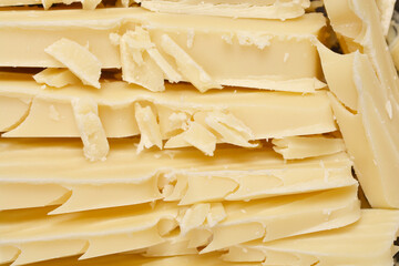 A detailed texture of white chocolate carved into rough, uneven shavings and slices fills the...
