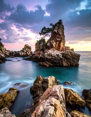 Coastal vista showing craggy rocks, water, and a dramatic sunset