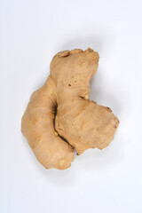 A piece of fresh ginger root with its light brown skin is isolated on a plain white background