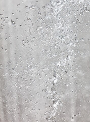 A spray of water droplets on a gray surface