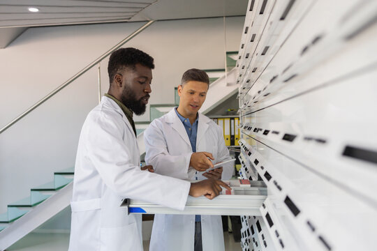 Pharmacist with colleague examining medicines in drawer at pharmacy