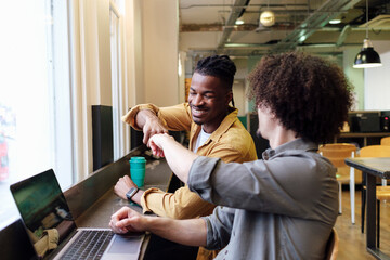 Smiling business colleagues giving fist bump at workplace