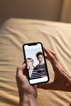 Hand holding smartphone browsing e-commerce website in casual setting