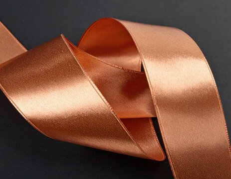 Satin ribbon loops and swirls, bronze color on dark surface