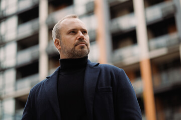 Adult man in coat and black turtleneck on city street
