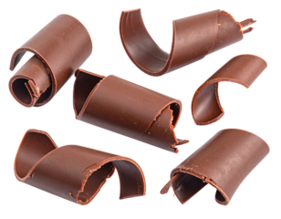 Scattered chocolate curls isolated on white background. Close-up of cocoa shavings for cake or ice cream decoration.