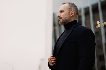 Confident man in elegant coat standing on city street